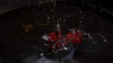 Red cherries drop in an oily pan full of water causing the water to jump Stock Footage 91205947
