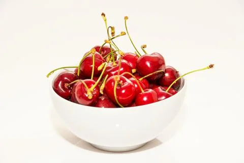 Red cherries inside a white cup on a white background Фото