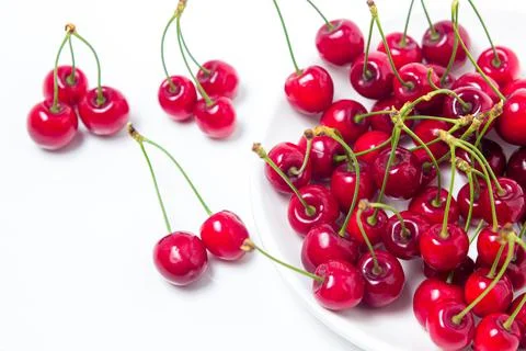 Red cherries on a white plate on a white background. Sweet cherry with tails Stock Photos