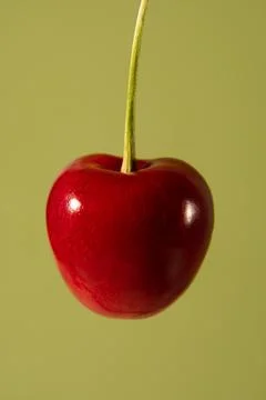 Red cherry on a delicate green background. Stock Photos