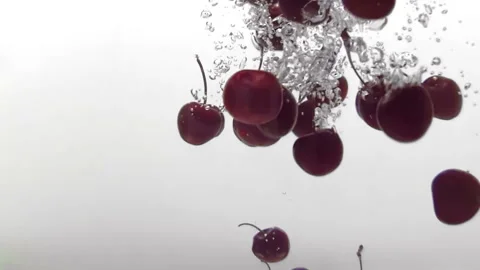 Red cherry dropping into water and splashing on white background Stock Footage 236746798