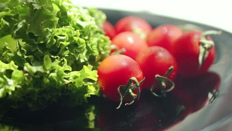 Red cherry fresh tomatoes and green salad under the sun rays Stock Footage 133344685