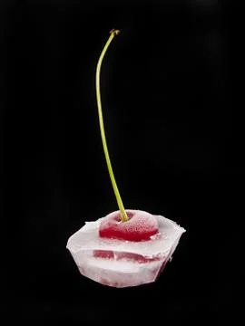 Red cherry in ice on a black background Stock Photos