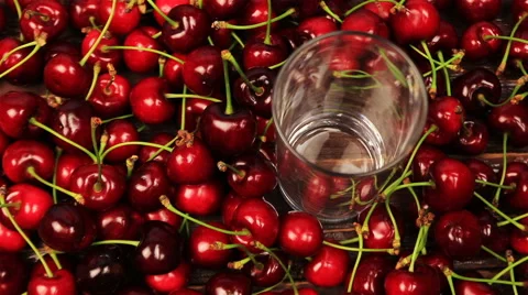 Red cherry juice being poured in a glass on cherry background Stock Footage 63828047