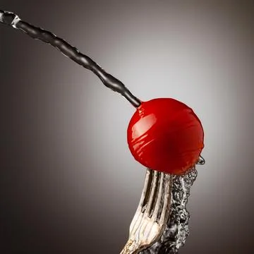 Red cherry tomato on a silver fork. A jet of water, splashes of water. Black Stock Photos