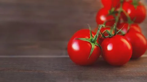 Red cherry tomatoes on branch on old wooden brown background, 16:9 Stock Photos