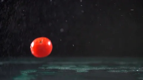 Red cherry tomatoes fall on wet surface under pouring water Video stock 126950964