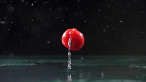 Red cherry tomatoes fall on wet surface causing water drops Stock Footage 132474074