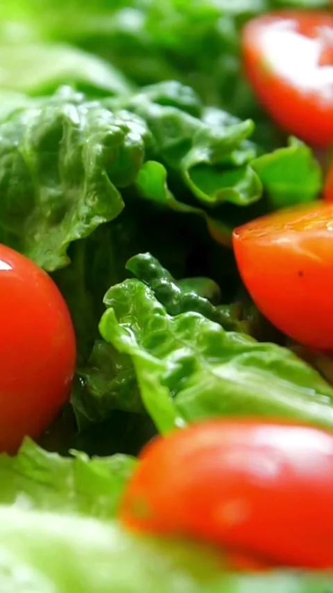 Red cherry tomatoes falling onto green lettuce leaves salad Stock Footage 331991688