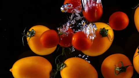 Red cherry tomatoes falling into water with orange tomatoes. Slow motion 스톡 동영상 77837059