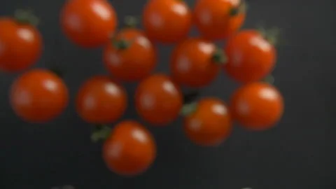 Red cherry tomatoes fly beautifully on black background Stock Footage 97883839