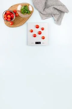 Red cherry tomatoes on gray digital kitchen scales. Near bowl with tomatoes,  Stock Photos