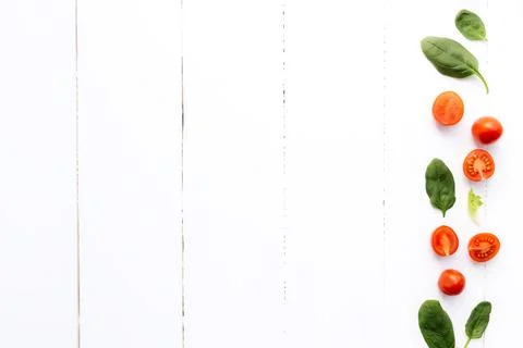 Red cherry tomatoes, green spinach leaves on white background. Healthy eating Stock Photos