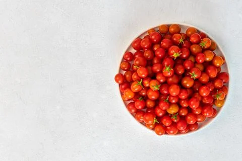 Red cherry tomatoes in a light dish on a light background, vegetarian product Stock Photos