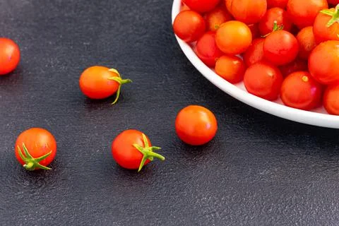 Red cherry tomatoes in a light dish on a dark background, vegetarian product, Stock Photos