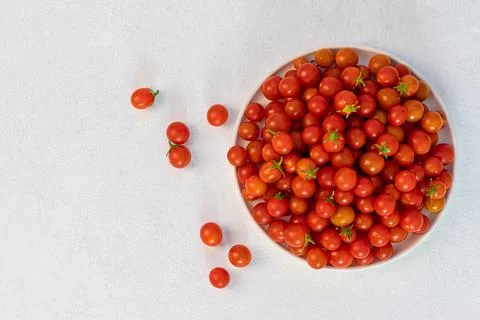 Red cherry tomatoes in a light dish on a light background, vegetarian product Stock Photos