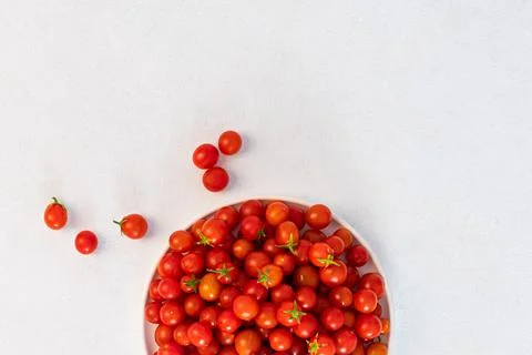 Red cherry tomatoes in a light dish on a light background, vegetarian product Stock Photos