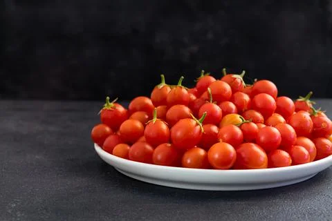 Red cherry tomatoes in a light dish on a dark background, vegetarian product, Stock Photos