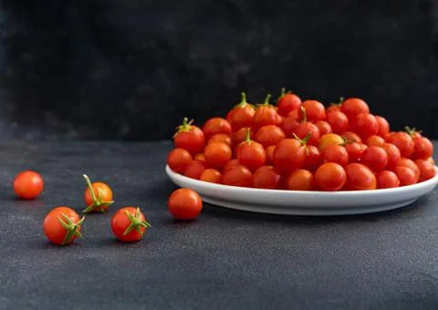 Red cherry tomatoes in a light dish on a dark background, vegetarian product, Stock Photos