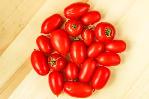 Red cherry tomatoes plum shape ripe on wooden table background. Seasonal market Stock Photos