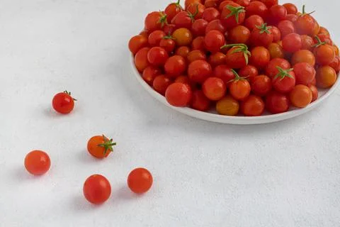 Red cherry tomatoes in a white dish on a light, minimalism Stock Photos