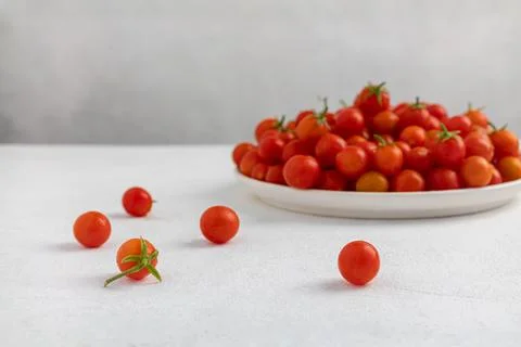 Red cherry tomatoes in a white dish on a light, minimalism Stock Photos