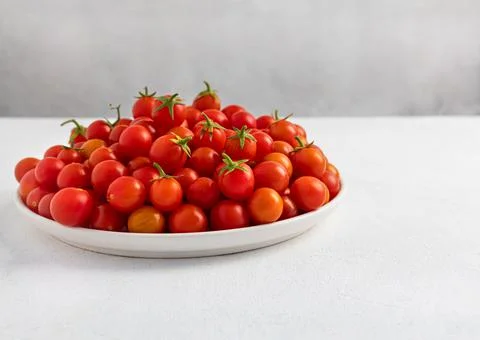 Red cherry tomatoes in a white dish on a light, minimalism Stock Photos