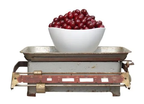 Red cherry in a white cup on old mechanical scales isolated on white backgrou Stock-Fotos