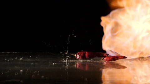 Red chili falling down with flames in the background in slow motion Stock Footage 88807880
