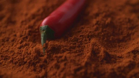Red chili pepper falling on chili powder. Slow Motion. Stock Footage 79475192