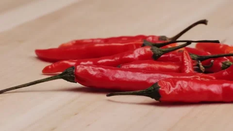 A red chilli pepper vegetable laying on a wooden table close-up The pepper Stock Footage 275844817