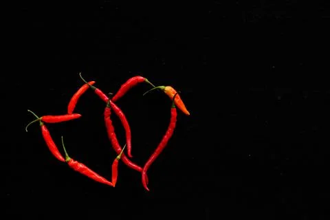 Red chillis arranged in the shape of two hearts intertwined Stock Photos