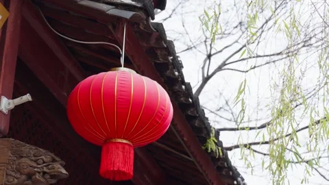 Red Chinese Lantern Swaying Beneath Traditional Roof in Garden Setting Stock Footage 312450962
