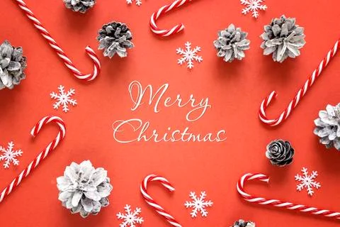 Red Christmas background with congratulation, candy canes and pine cones. Stock Photos