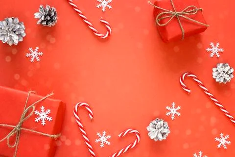 Red Christmas background with gift boxes, pine cones and candy canes. Copy sp Stock Photos