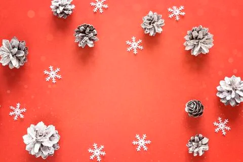 Red Christmas background with pine cones and snowflakes. Copy space for text. Stock Photos