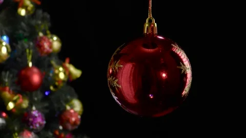 A red Christmas ball with a pattern rotates near a decorated Christmas tree Stock Footage 255120223