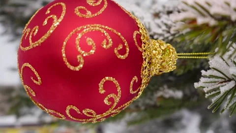 A red Christmas ball with patterns hangs on the snow-covered branches Stock Footage 258645328