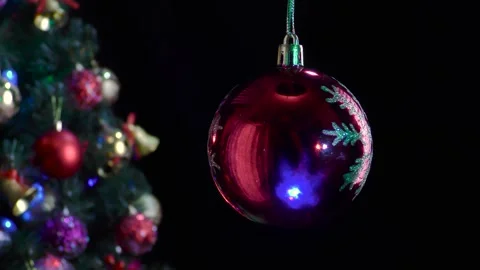 A red Christmas ball with a snowflake pattern rotates near Christmas tree Stock Footage 255120225