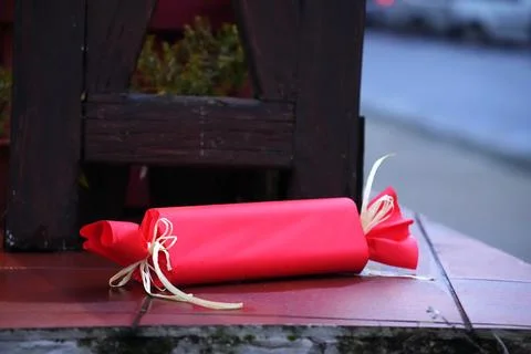 A red Christmas cracker tied with string, lying on a red surface. Stock Photos
