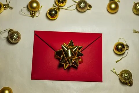 Red Christmas envelope with gold bow and baubles on table Stock Photos