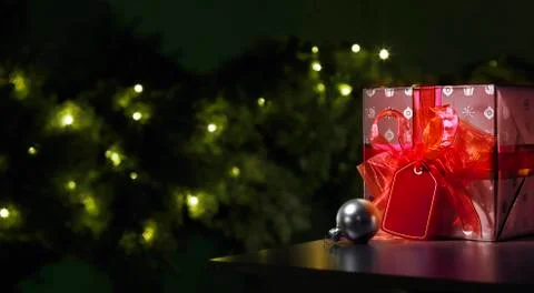 Red Christmas gift with a tree in the background Stock Photos