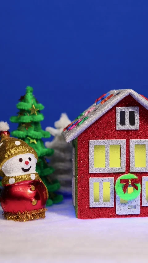 Red Christmas house surrounded by two snowmen and a snake figurine Stock Footage 299271668