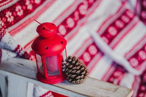 Red Christmas lantern with a pine cone on a wooden chair against a cozy winter b Stock Photos