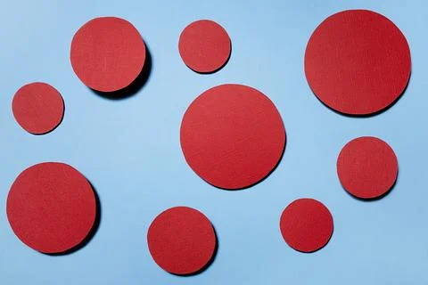 Red circles soar on blue background in hard light with shadows as abstract co Stock Photos