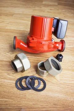Red circulation pump for heating system and fasteners for it lies on the floo Stock Photos