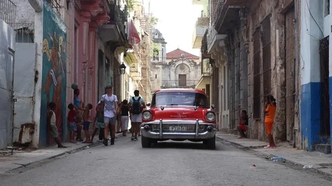 A Red Classic Car Drives Down a Narrow Street in Havana, Cuba 스톡 동영상 124809861