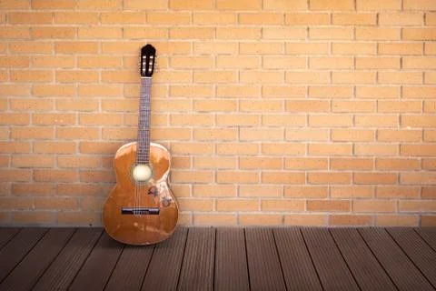 Red classical guitar guitar in studio with floor and orange brick wall Stock Photos