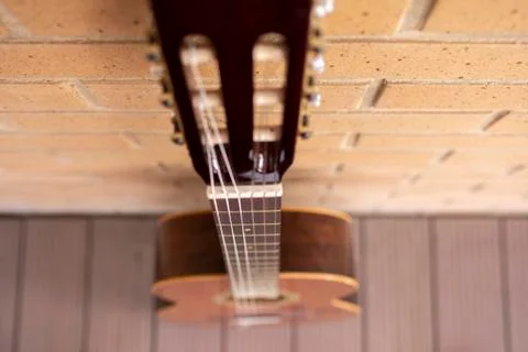 Red classical guitar guitar in studio with floor and orange brick wall Stock Photos