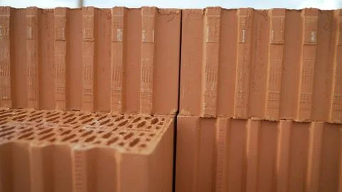 Red clay bricks are stacked on wooden pallets. New bricks on the construction Foto stock